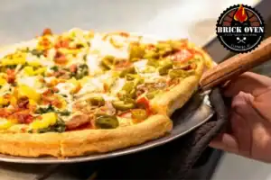 Fresh pizza being served from a restaurant oven with toppings and jalapeños