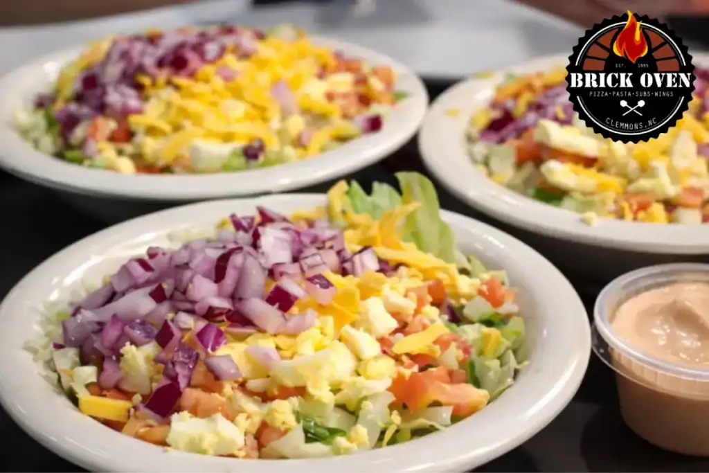 Greek restaurant salads served in bowls with fresh chopped vegetables, cheese, and dressing.